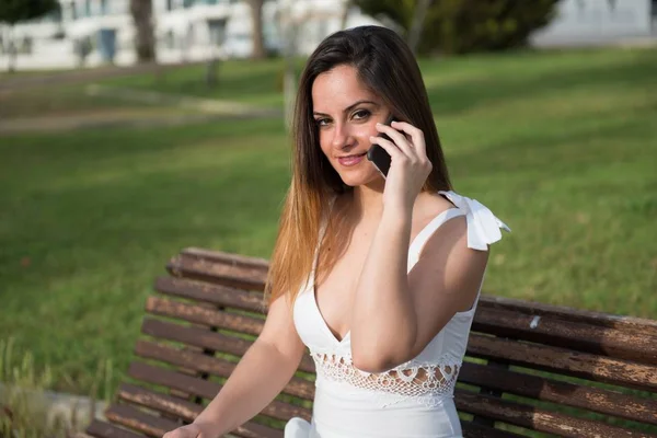 Beautiful young girl in a park talking to mobile — Stock Photo, Image