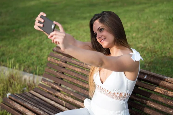 Krásná mladá dívka v parku, takže selfie — Stock fotografie