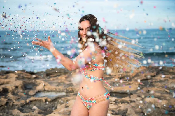 Vacker ung flicka i stranden med konfetti — Stockfoto