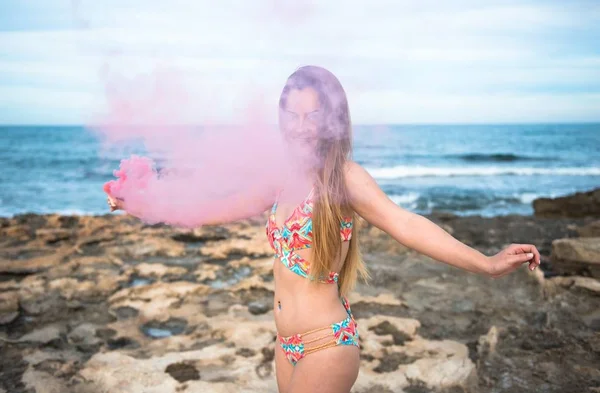 Vacker ung flicka med rök bomb i stranden — Stockfoto