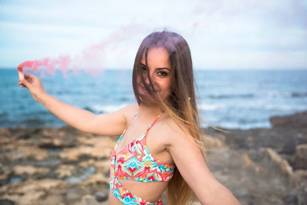 Vacker ung flicka med rök bomb i stranden — Stockfoto