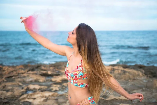 Belle jeune fille avec bombe à fumée sur la plage — Photo