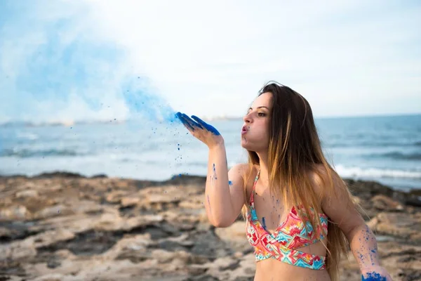 Vacker ung flicka i stranden med blå färg holi — Stockfoto