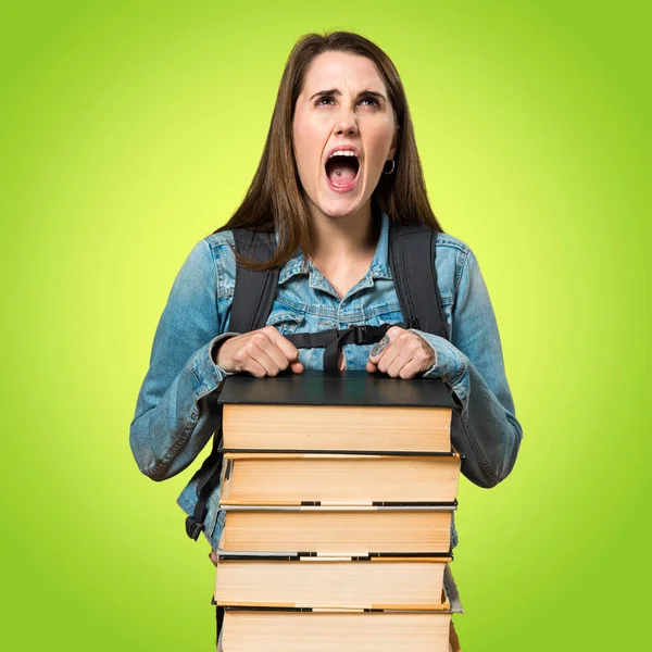 Adolescente menina estudante com um monte de livros e gritando — Fotografia de Stock