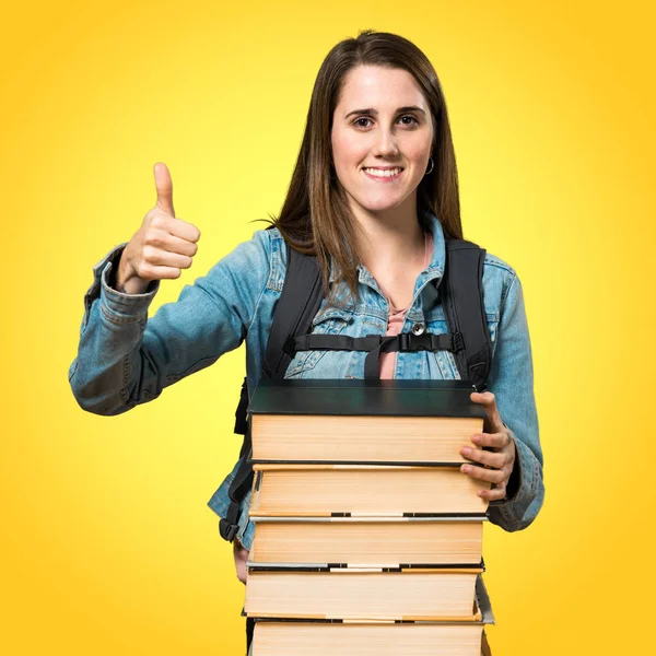 Adolescente estudiante chica con un montón de libros y con el pulgar hacia arriba — Foto de Stock