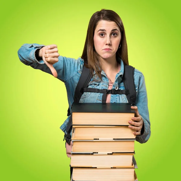 Adolescente estudiante chica con un montón de libros y haciendo mala señal — Foto de Stock