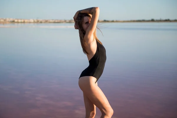 Junges Mädchen im schwarzen Badeanzug am Strand — Stockfoto