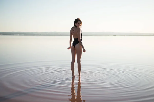 Giovane ragazza in costume da bagno nero in spiaggia — Foto Stock