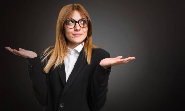 Koyu arka plan üzerinde önemsiz jest yapma genç iş kadını