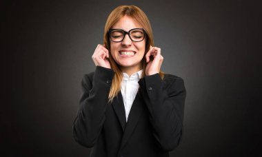 Kulakları koyu arka plan üzerinde kapsayan genç iş kadını