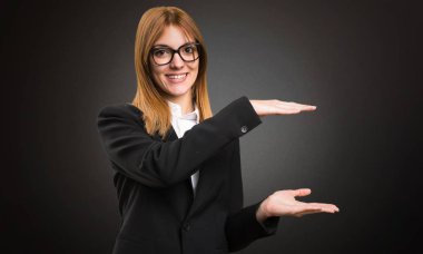 Bir şey Koyu arka plan üzerinde tutan genç iş kadını