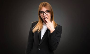 Koyu arka plan üzerine kusma jest yapma genç iş kadını