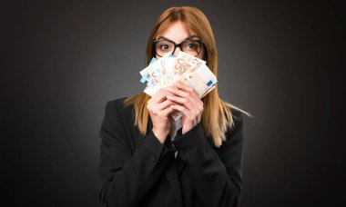 Koyu arka plan üzerinde bir sürü para alarak genç iş kadını