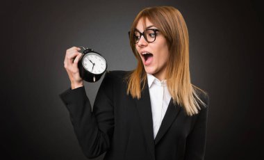 Vintage saat koyu arka plan üzerinde tutan genç iş kadını