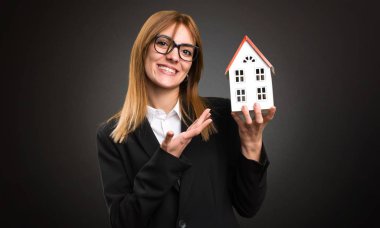 Koyu arka plan küçük bir ev tutarak genç iş kadını