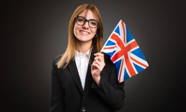 Bir Amerika Birleşik Devletleri bayrağı koyu arka plan üzerinde tutan genç iş kadını