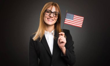 Bir Amerikan bayrağı koyu arka plan üzerinde tutan genç iş kadını