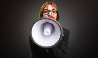 Bir megafon koyu arka plan üzerinde tutan genç iş kadını