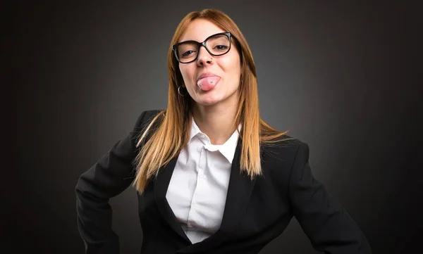 Young business woman taking out her tongue on dark background — Stock Photo, Image
