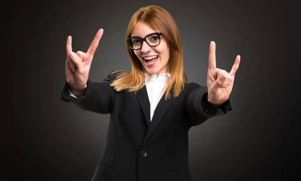 Jonge zakelijke vrouw maken hoorn gebaar op donkere achtergrond — Stockfoto