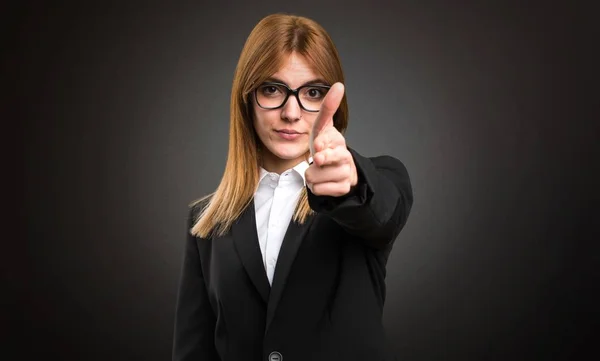 Young business woman making gun gesture on dark background — Stock Photo, Image