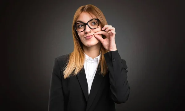 Jeune femme d'affaires faisant un geste de silence sur fond sombre — Photo