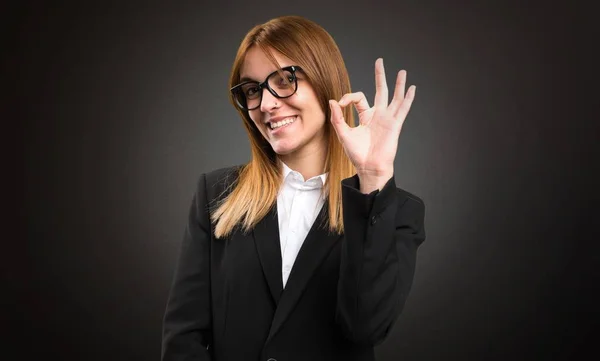 Jonge zakenvrouw Ok ondertekenen op donkere achtergrond maken — Stockfoto