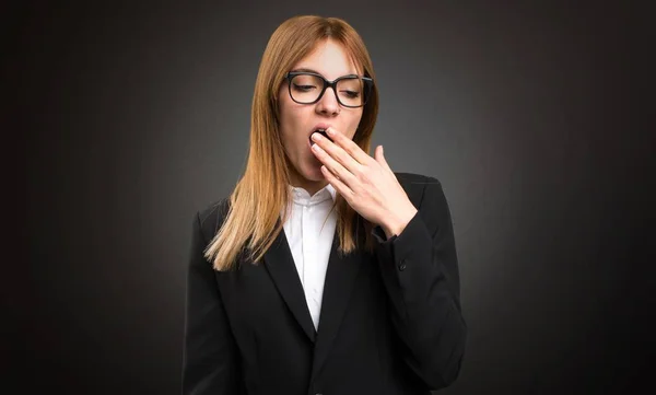 Young business woman yawning on dark background — Stock Photo, Image