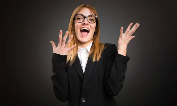 Jonge zakelijke vrouw maken verrassing gebaar op donkere achtergrond — Stockfoto