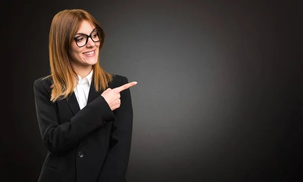 Joven mujer de negocios señalando el lateral sobre fondo oscuro — Foto de Stock