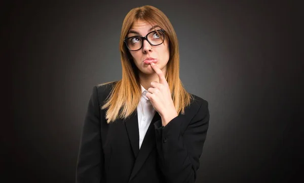 Junge Geschäftsfrau zweifelt an dunklem Hintergrund — Stockfoto