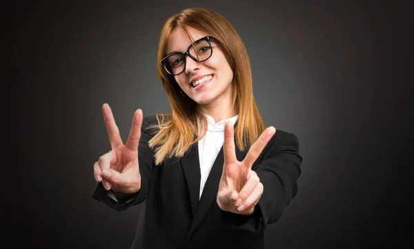 Mladí obchodních žena dělat vítězství gesto na tmavém pozadí — Stock fotografie