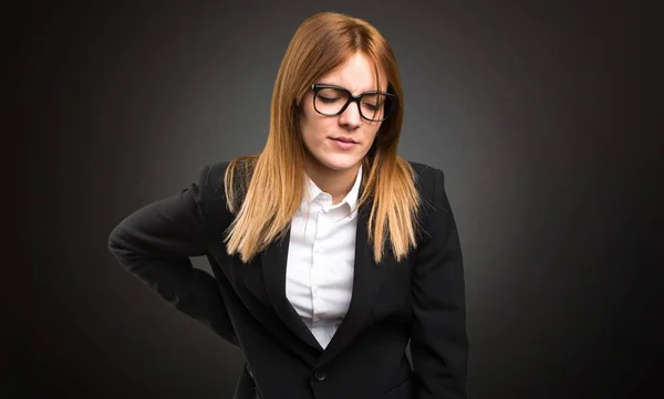 Young business woman with back pain on dark background — Stock Photo, Image