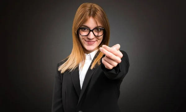 Young business woman doing coming gesture on dark background — Stock Photo, Image