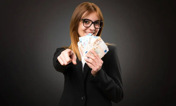 Fiatal üzleti nő vesz egy csomó pénzt a sötét háttér — Stock Fotó