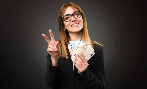 Joven mujer de negocios tomando un montón de dinero en el fondo oscuro — Foto de Stock