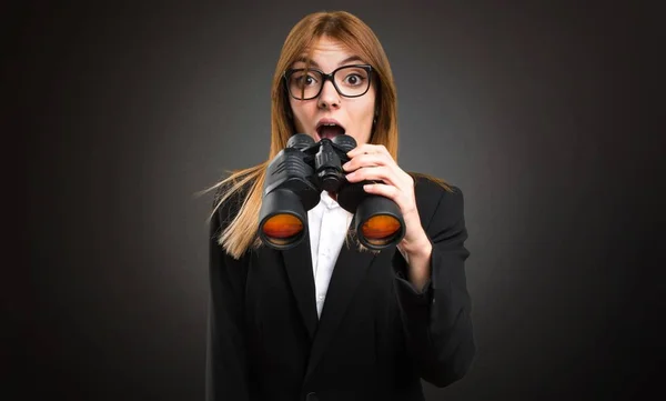 Young business woman with binoculars on dark background — Stock Photo, Image