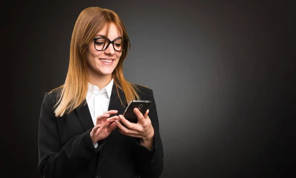 Joven mujer de negocios hablando con móvil sobre fondo oscuro —  Fotos de Stock