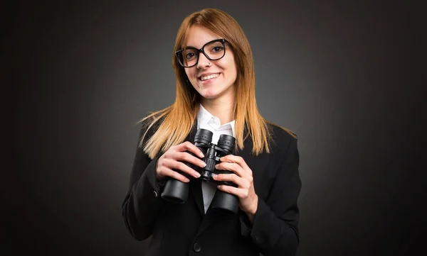 Ung affärskvinna med kikare på mörk bakgrund — Stockfoto