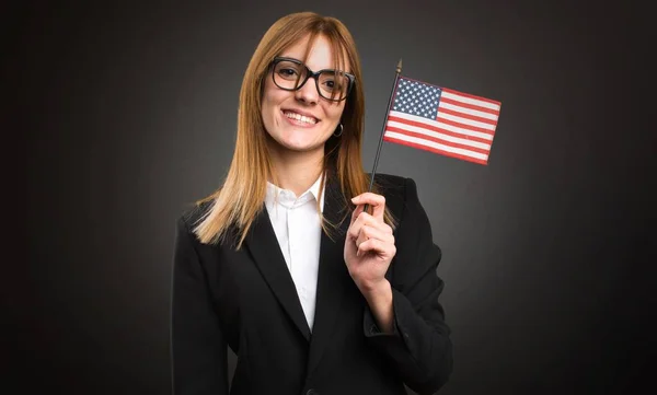 暗い背景にアメリカの国旗を保持している若いビジネス女性 — ストック写真