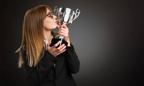 Jeune femme d'affaires tenant un trophée sur fond sombre — Photo