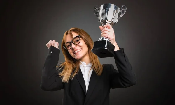 Jovem mulher de negócios segurando um troféu no fundo escuro — Fotografia de Stock