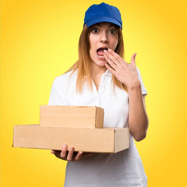 Lieferfrau macht Überraschungsgeste auf buntem Hintergrund — Stockfoto