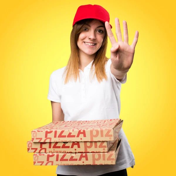 Mulher de entrega de pizza contando quatro em fundo colorido — Fotografia de Stock