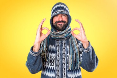 Adam kış giysileri renkli arka plan üzerinde oturum Tamam yapma ile