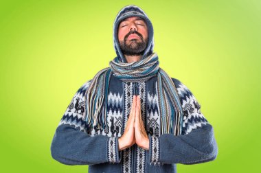 Kış giysileri renkli arka plan üzerinde zen pozisyonda olan adam