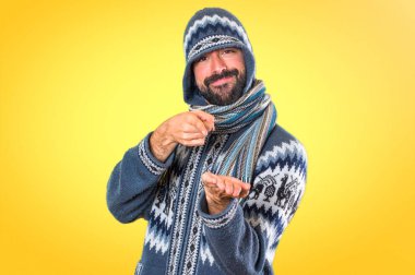 Adam bir şey renkli arka plan üzerinde tutan kış giysileri ile