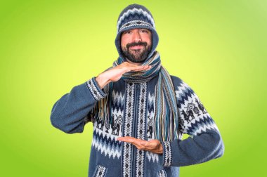 Adam bir şey renkli arka plan üzerinde tutan kış giysileri ile