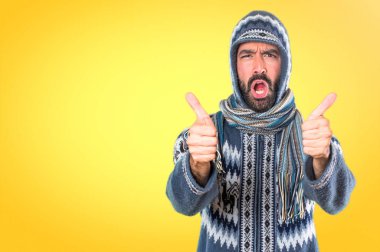Kış giysileri renkli arka plan üzerinde başparmak ile olan adam