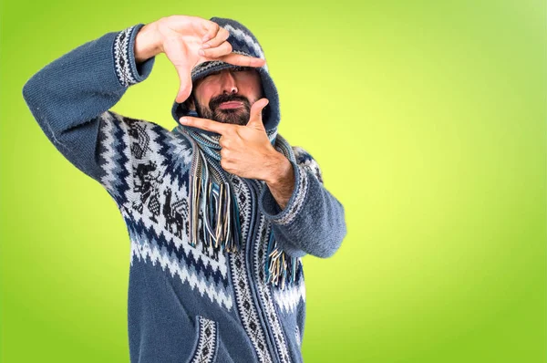 Hombre con ropa de invierno enfocándose con sus dedos en ba colorido — Foto de Stock